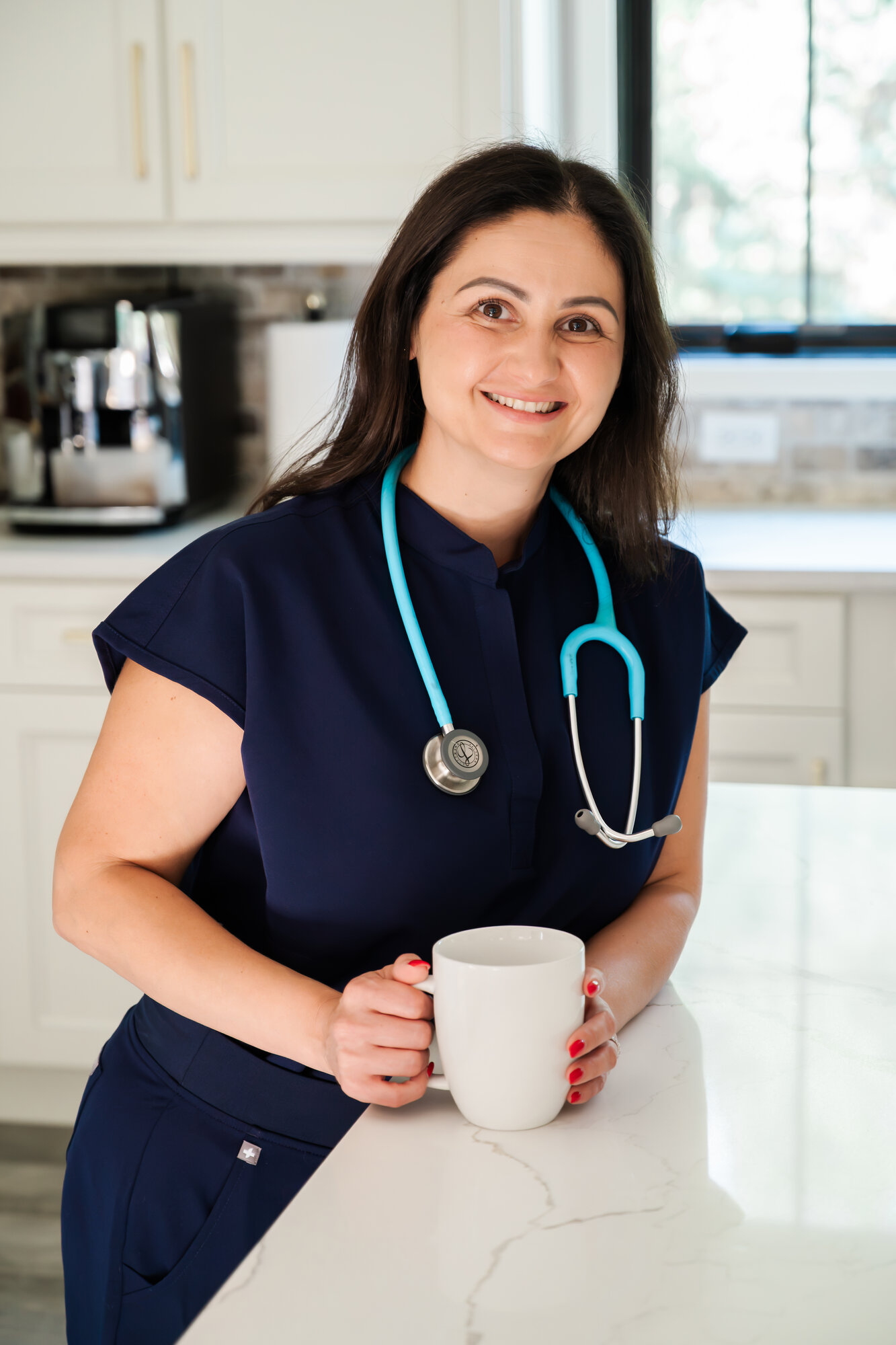 Loreta Labode, RN, smiling in navy scrubs with her stethoscope
