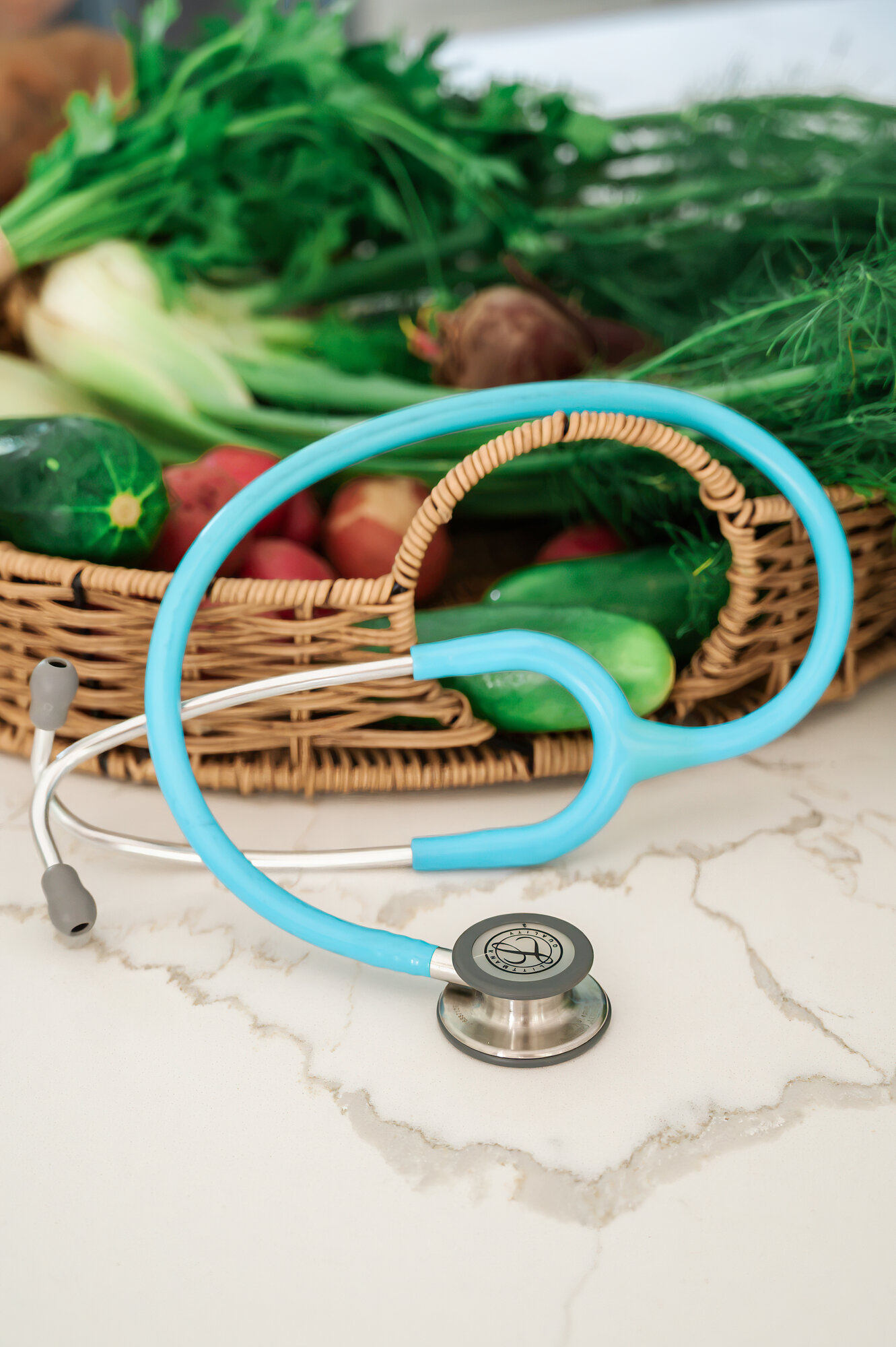 A basket of fresh vegetables beside a teal stethoscope
